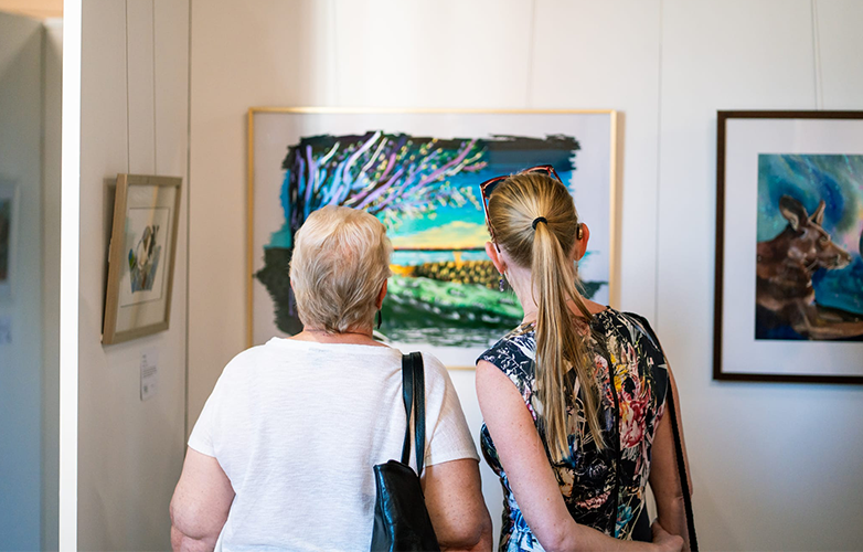 Community members pause to reflect on the creativity and stories behind the exhibition pieces.
