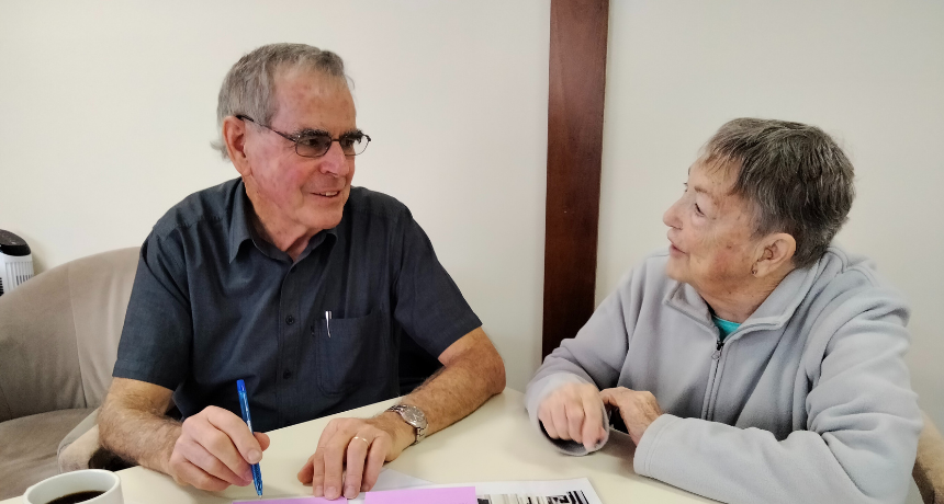 Three people sitting at a table during a co-design workshop talking with each other about their insights